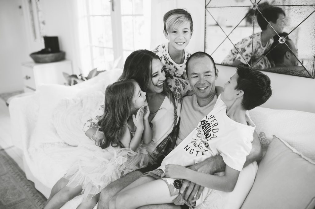 Clarissa Grace of Waking Up In Paris seated on a couch with her husband, two sons, and daughter. 